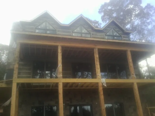 Dormers and porch framing on a large log home under construction — Roof Coating work by our crew in Linden