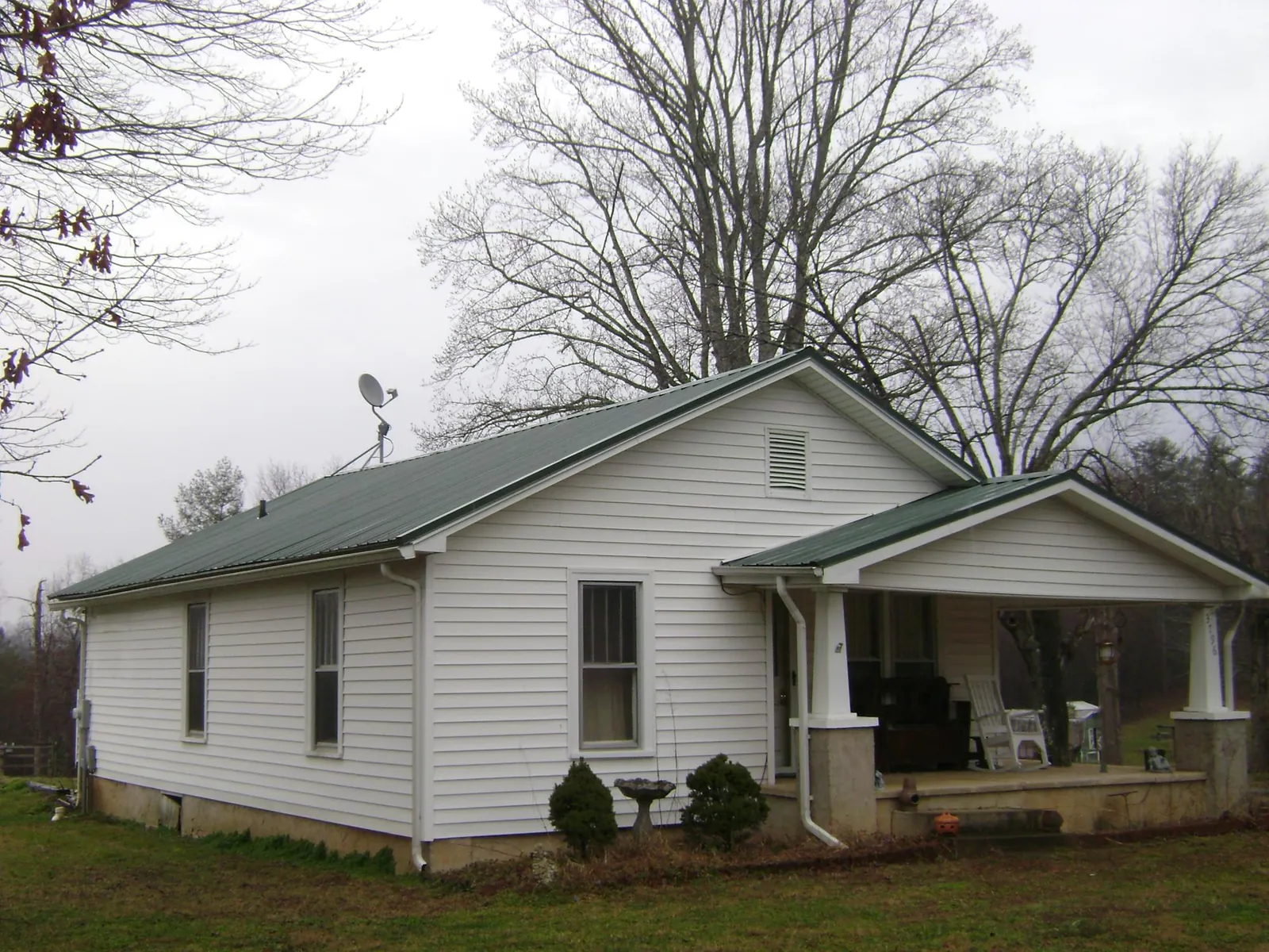 Green metal roof on a white bungalow with a side porch in Linden